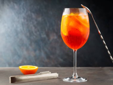 Aperol sprey kokteyli ve arka planda çelik çubuk aletleri. Kokteyl Aperol Spritz ve portakal dilimi. Boşluğu kopyala