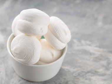 Zephyr lokumları gri arka planda kasede. Betonda tatlı marşmelovları. Boşluğu kopyala