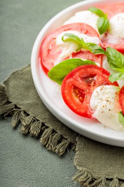 Domatesli salata, mozzarella ve yeşil arka planda fesleğen. Kapat.