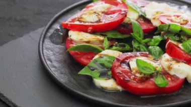 Domatesli İtalyan Caprese Salatası, mozzarella ve koyu arkaplanda fesleğen. Dönen kamera görüntüsü