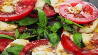 Siyah tabakta Caprese salatası. Mozzarella ve fesleğen yapraklı domates salatası. Organik yiyecekler