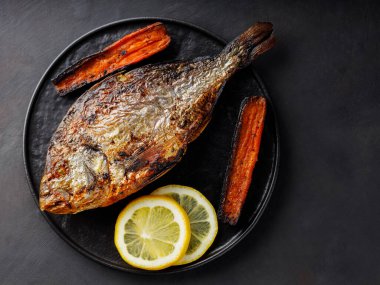 Izgara havuçlu Dorado balığı ve koyu arkaplanda limon. Üst Manzara. Boşluğu kopyala