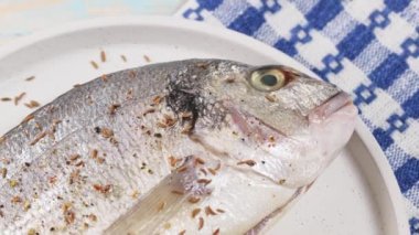 Limonlu çiğ dorado balığı ve beyaz tabağa kimyon serpiştirilmiş. El kamerasıyla.