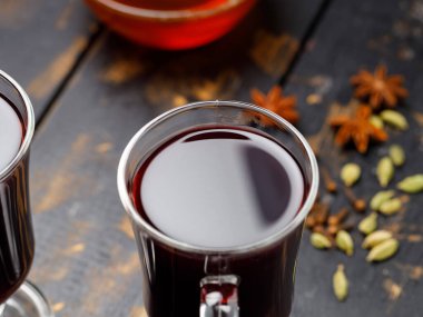 Koyu ahşap tahtalarda iki bardak sıcak şarap ve malzeme. Baharatlı sıcak içecek konsepti