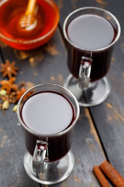 Koyu ahşap tahtalarda iki bardak sıcak şarap ve malzeme. Baharatlı sıcak içecek konsepti