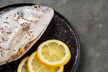 Taze çiğ dorado balığı ve koyu arkaplanda limon dilimleri. Üst Manzara. Boşluğu kopyala