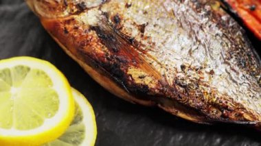 Siyah tabakta limon sümüğü olan fırında altın dorado balığı. Kamera hareketini yukarı kaldır