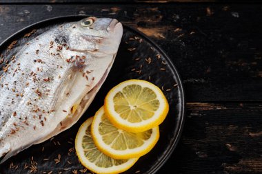 Koyu arkaplanda limonlu taze dorado balığı. Akdeniz mutfağı. Boşluğu kopyala