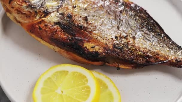 在白盘上烤着柠檬和香料的多拉多鱼 倾斜向上相机运动 — 图库视频影像
