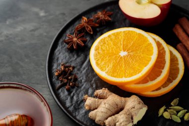 Sıcak şarap baharatları ve siyah tabakta malzemeler. Kapat.