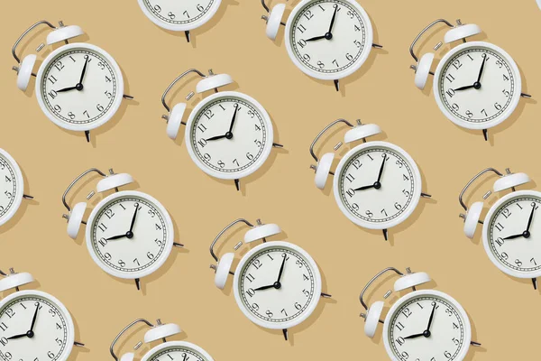 Pattern with White Alarm Clock on Beige Background, Top View