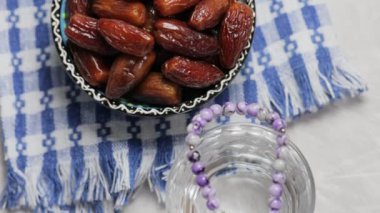 Kurutulmuş hurma kasesi, bir bardak su ve gri arkaplanda dua boncukları, Ramazan Suhoor kavramı