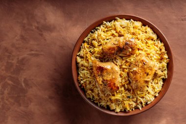 Tavuk Biryani in Clay Bowl on Brown Background, Copy Space, Top View