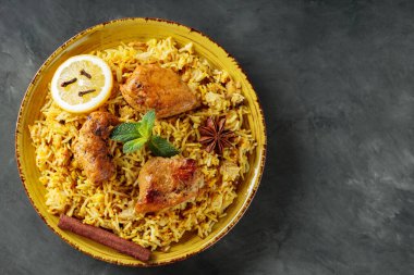 Biryani Tavuğu Sarı Tabakta Yıldız Anason, karanfil, taze nane ve limon ile Karanlık Arkaplanda, Kopya Boşluğu, Üst Görünüm