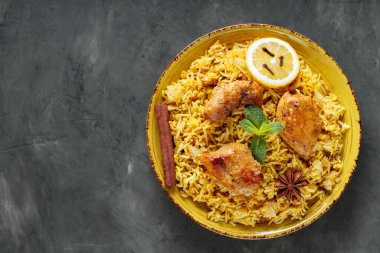 Biryani Tavuğu Sarı Tabakta Yıldız Anason, karanfil, taze nane ve limon ile Karanlık Arkaplanda, Kopya Boşluğu, Üst Görünüm