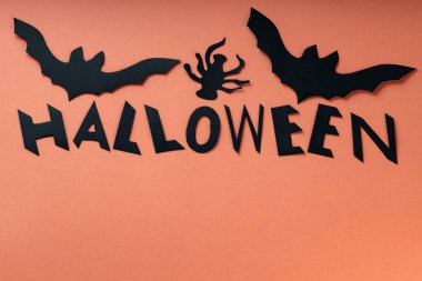 DIY Halloween Bat and Spider Paper Cutouts with Halloween Lettering on Orange Background, Copy Space clipart