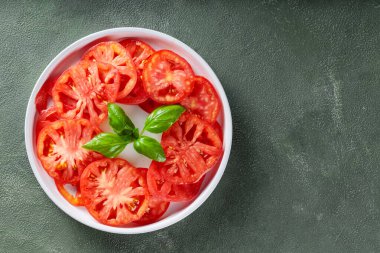 Beyaz Tabakta taze fesleğenle canlı domates dilimleri, Yeşil desenli arka plan, Üst Görünüm, Kopyala Boşluk