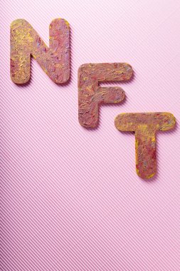 NFT Letters with Textured Colorful Paint Finish on Pink Background, Non-Fungible Token Concept, Copy Space clipart