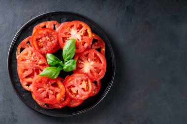 Taze fesleğenle sulu domates dilimleri Kara Tabakta Yapraklar, Koyu Gri Döşemeli Arka plan, Üst Görünüm, Boşluğu Kopyala