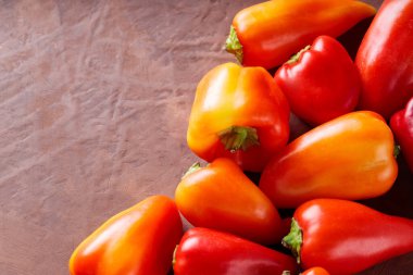 Vejetaryen ve Vejetaryen Yemekleri İçin Kahverengi Arkaplanda Olgun Kırmızı ve Turuncu Capsicum, Kopyalama Boşluğu