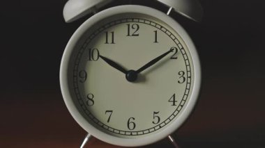 Beyaz Mekanik Analog Alarm Saati 'nin Karanlık Arkaplanda Eğik Kamera Hareketi