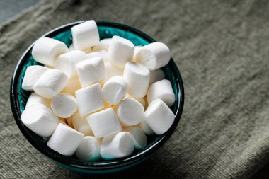 Turkuaz kasede yeşil arkaplanlı Lezzetli Marshmallow Atıştırması
