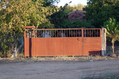 Evin arka planında metal çitler var.