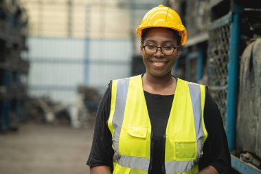 Siyahi akıllı Afrikalı kadın işçi fabrika işyerinde gülümseyerek ayakta duruyor.