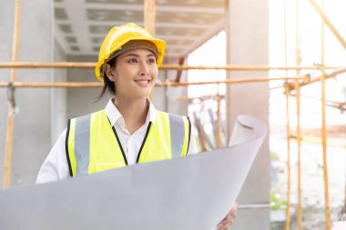 Çalışan kadın mimar mutlu bir gülümseme kat planı inşaatçısı inşaat alanında çalışıyor.