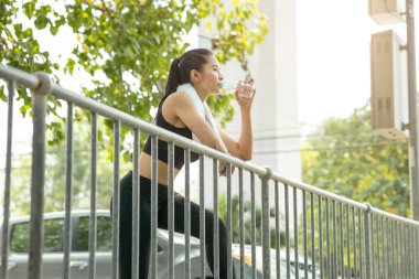 spor yapan Asyalı bayan sabah içme suyu içiyor sağlıklı yaşam tarzı için koşuyor.