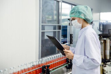 Gıda ve içecek endüstrisi çalışanı konveyör bandı üretim hattında çalışıyor. Temiz ve hijyen alanı olan içecek fabrikasında..