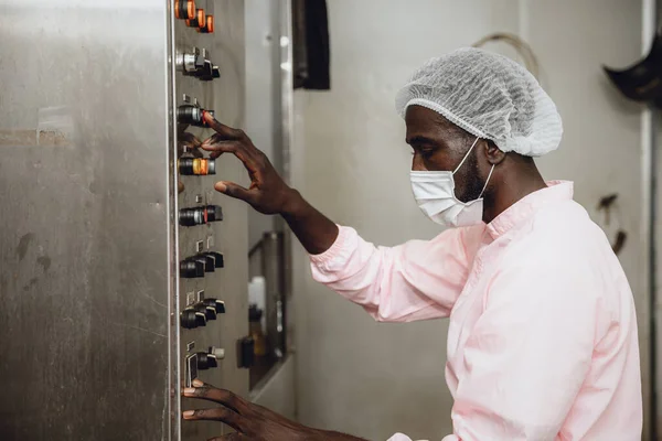 African Nigerian worker staff working control machine food and drink factory production process
