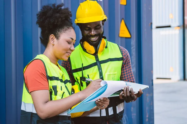 African American couple customs team staff worker working together with check list shipping order at port container yard enjoy work happy smile