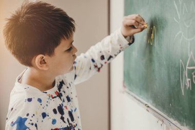 Asian boy happy smile enjoy education at school in classroom writing answer at chalkboards