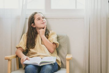 cute child girl reading a book and thinking new idea. bookworm nerdy smart kid learn and have a question