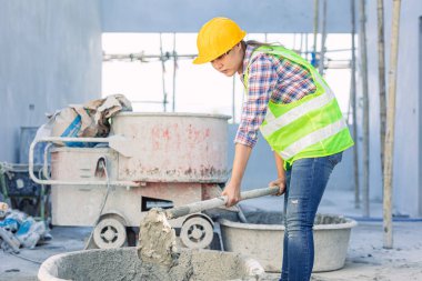 asian woman worker hardworking as a labor staff in construction site work mix concrete cement by hand