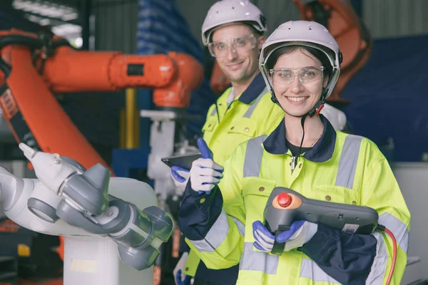 happy engineer team portrait thumbs up enjoy working together in modern metal factory with robotic arm