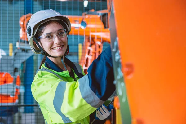 portrait happy woman worker with robot assembly machine in modern metal industry factory