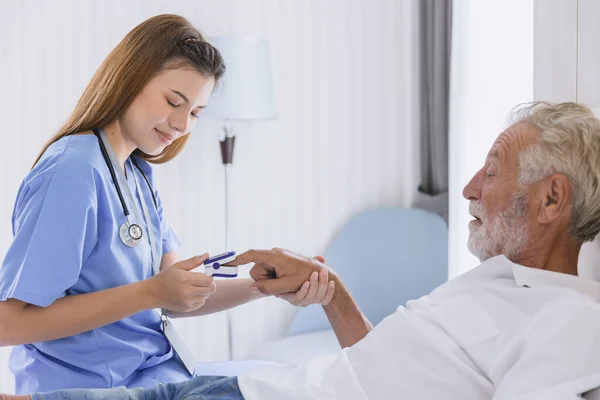 Nurse doctor working at home care medical checkup using fingertip pause oximeter measures blood oxygen saturation level senior elder