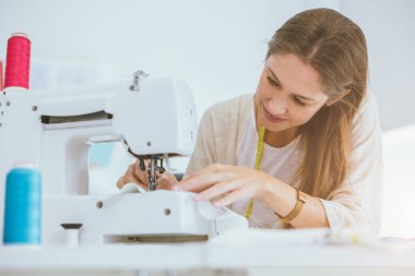 Profesyonel kostümlü kadın işi. Dijital dikiş makinesiyle terzi stüdyosunda mutlu olun.