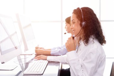Çağrı merkezindeki kadın mutlu bir şekilde çalışıyor. Müşteri destek ekibi CRM yazılımını kullanarak yardım ve irtibat kurmaktan keyif alır..