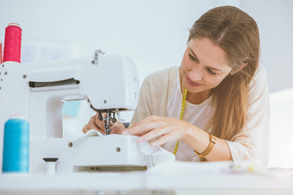 Профессиональная костюмерная женщина работает с цифровой швейной машинкой счастливы в портной студии