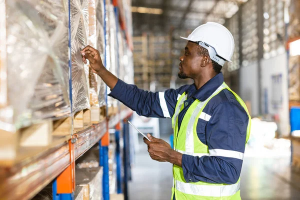 アフリカの黒人男性倉庫労働者は工場店舗での作業チェック棚在庫ラベルに焦点を当てる — ストック写真