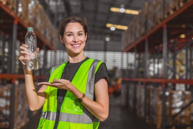 Su şişesi olan mutlu işçi sıcak iş yerinde temiz ve sağlıklı bir iş için temiz su içiyor.