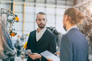 Makine fabrikasında çalışan iş adamı robot montaj fabrikası ekibi birlikte çalışıyor.