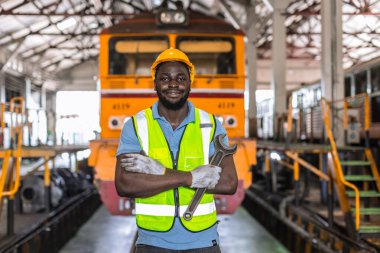 Portrait African black male worker work in Locomotive Repair Shops standing happy smiling with wrench clipart
