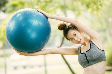 Güzel Asyalı mutlu kadın parkta spor yaparken eğleniyor. Sıska ve sağlıklı kız spor yapıyor..