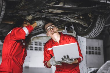 Tamirci erkek ekip çalışanı. Garajda otomatik kontrol altında birlikte çalışıyorlar.