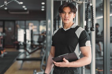 Spor salonunda duran erkek kas koçu ağırlık antrenörü. Akıllı fitneci yönetmen.