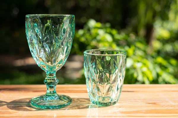 Uranium glass or Sapphire Crystal glass. Green tint color glassware vintage classic design old kitchenware on wooden table outdoor sunny light reflective.